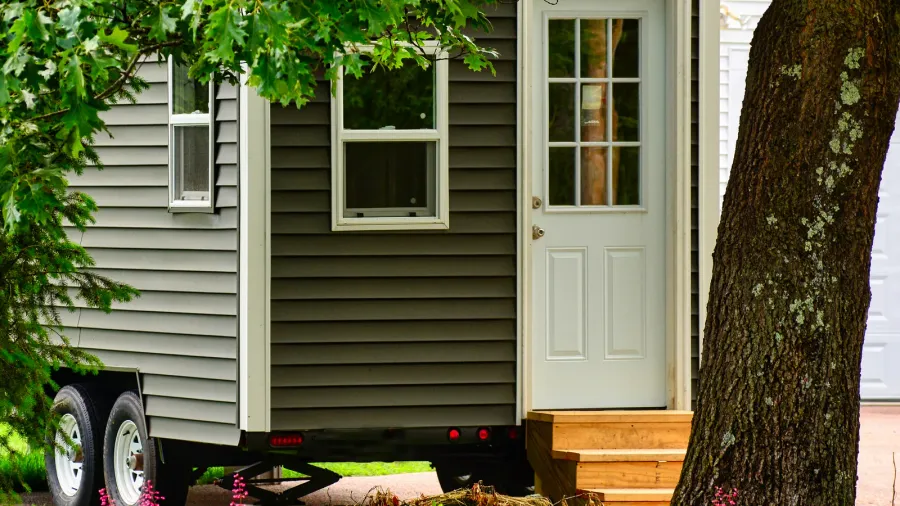 tiny home on wheels framed by trees and flowers