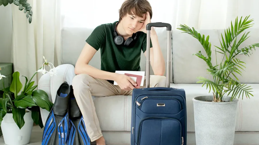 tourist boy with a suitcase and flippers stays at home