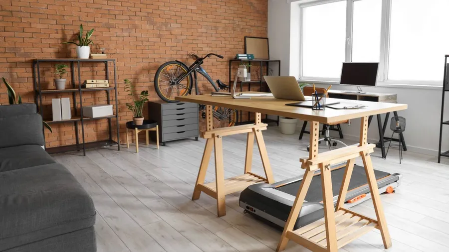 A modern workspace with a wooden desk, plants, and a bike on the wall.