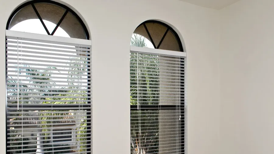 Two arched windows with blinds, allowing natural light to flow in.