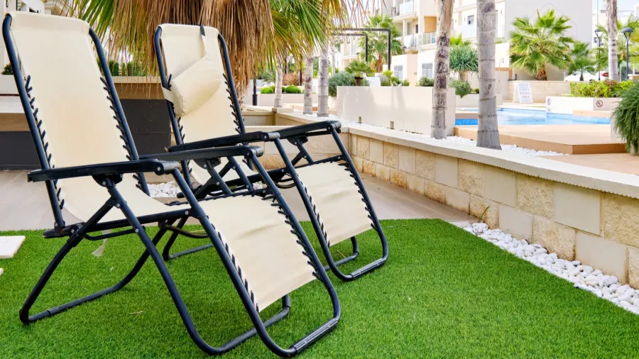 two empty lounge chairs on artificial lawn grass inside of