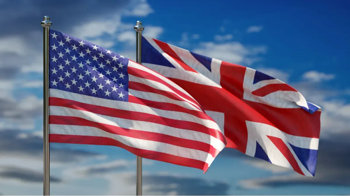 uk and usa national flag waving against cloudy sky background