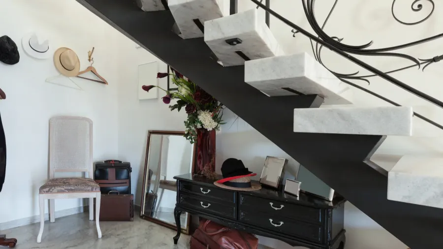 An interior staircase with a black metal frame and white steps, located next to a white wall with minimal decor.