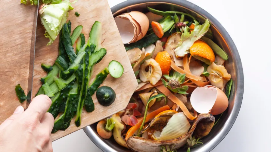 vegetable peels are thrown from cutting board into an iron
