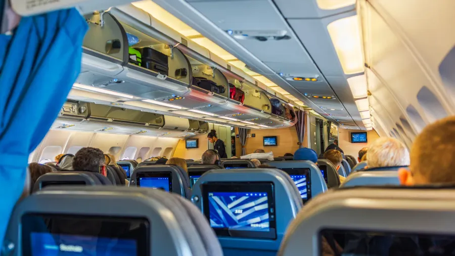 view of airplane economy class cabin showing passengers seated comfortably