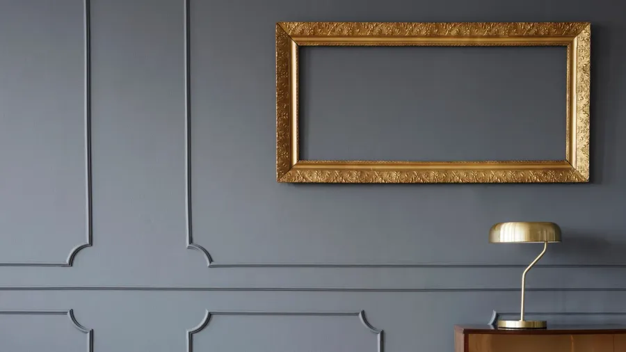 Wainscoting gray wall. Vintage wooden cabinet and an elegant empty golden frame.