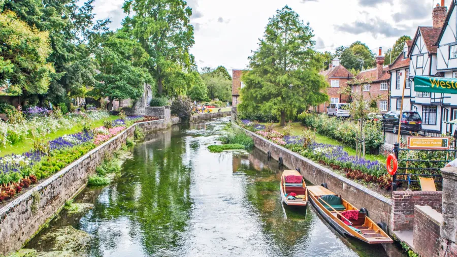 water channel with greenery houses and cloudy sky