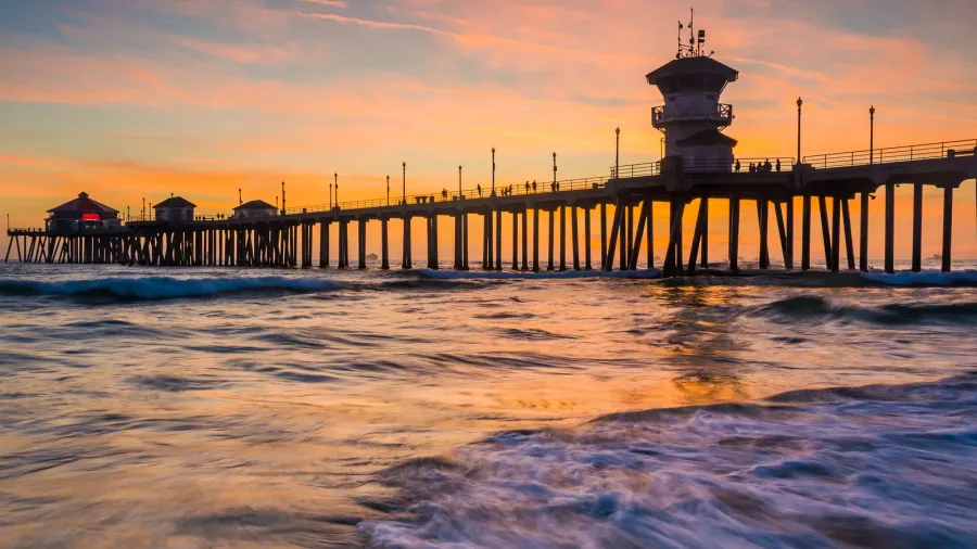 waves in the pacific ocean and the pier at sunset