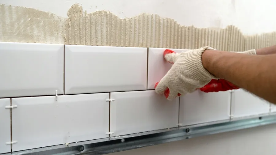 A man installing white ceramic tiles.