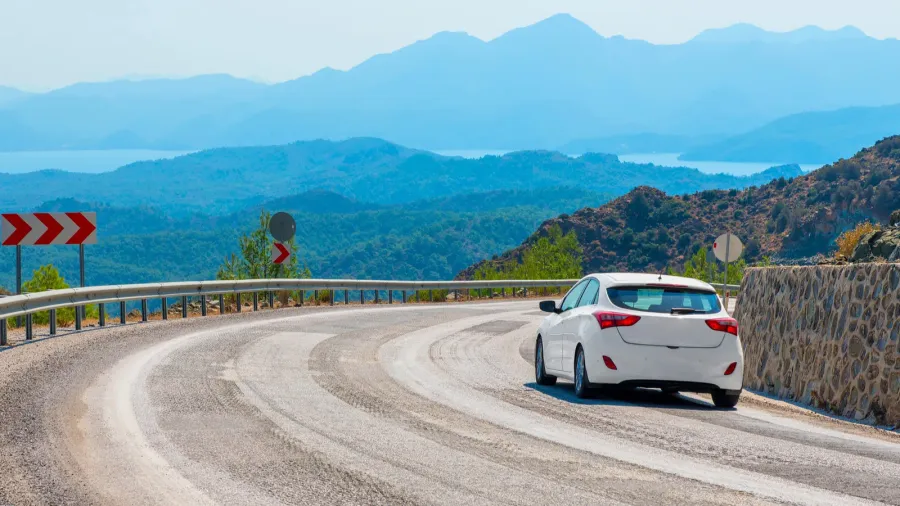 white car in turn a mountain road