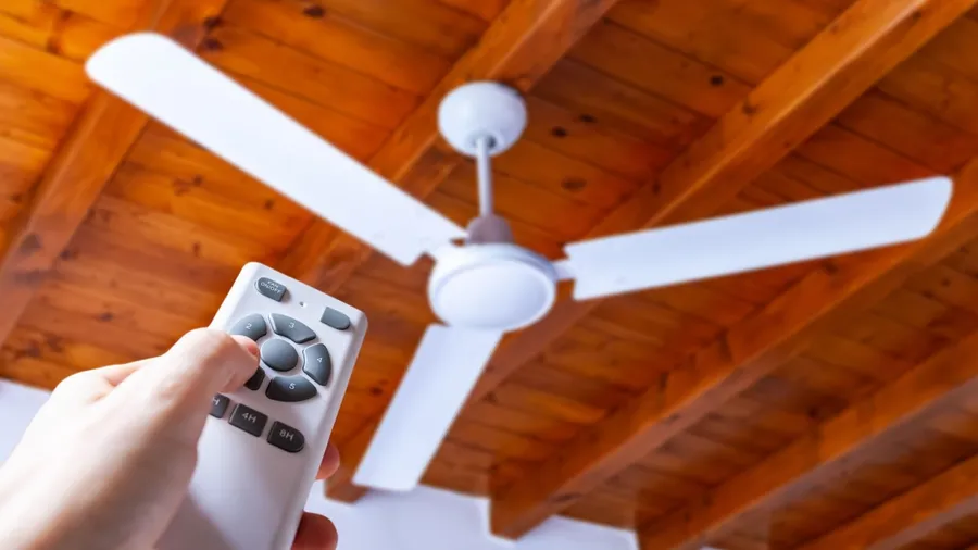 A person using remote to operate a ceiling fan.