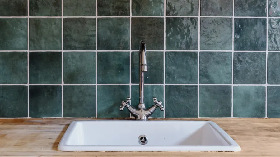 white sink and silver water faucet installed on wooden countertop
