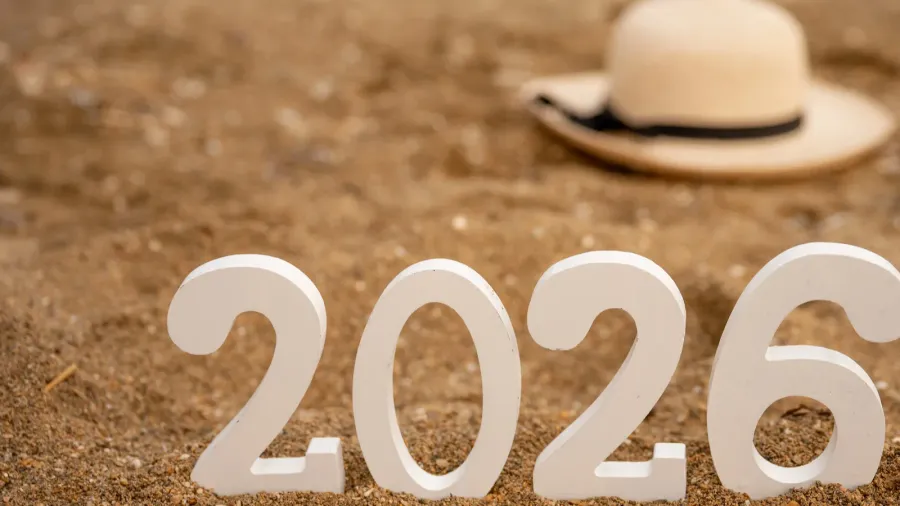 white wooden numbers 2026 standing on golden sand beach with