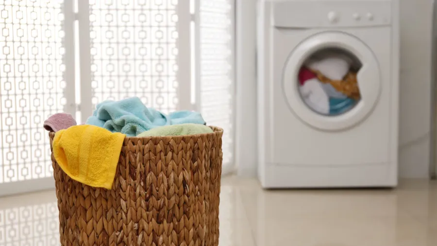 wicker laundry basket full of colorful towels on floor in