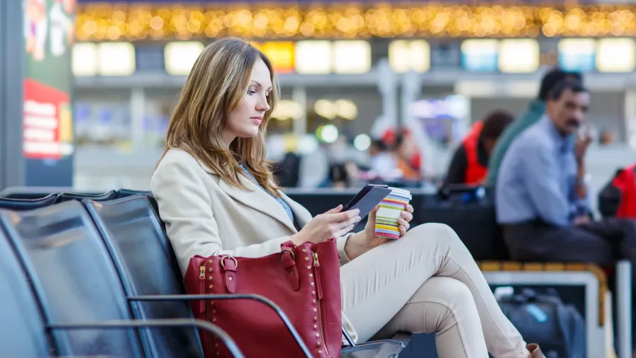 woman at international airport reading ebook and drinking coffe