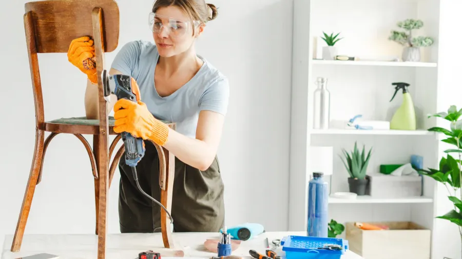 woman carpenter renovates an old chair in her cozy workshop
