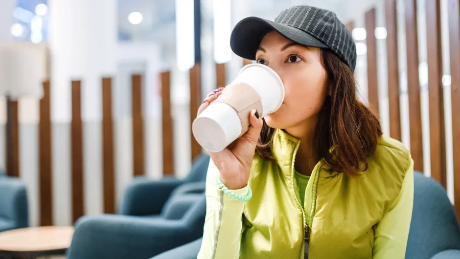 woman in a cafe drinking coffee with takeaway cup