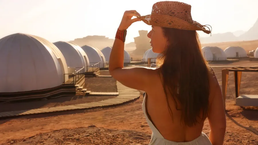 woman in a hat admiring a desert glamping site at