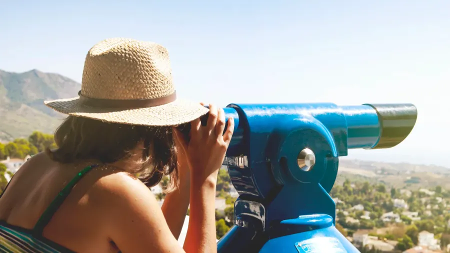 woman looking at landscape through a telescope vintage tone