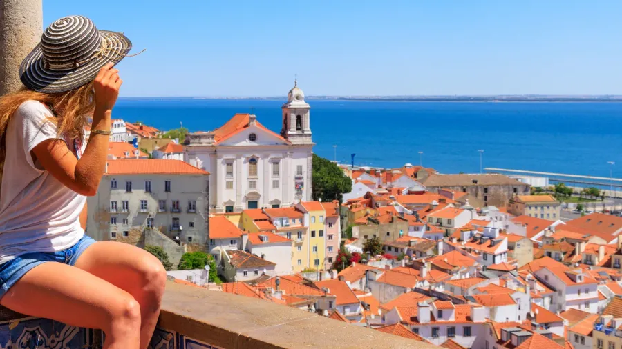 woman on balcony looking at panoramic view of lisbon in