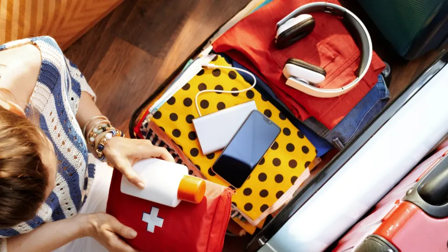 woman packing first aid kit and spf in open travel