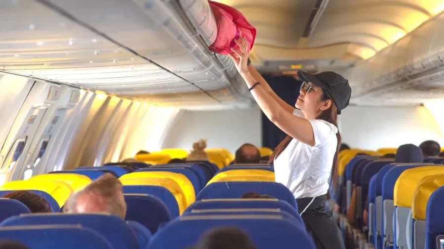 woman passenger traveler on boarding aircraft looking for empty overhead
