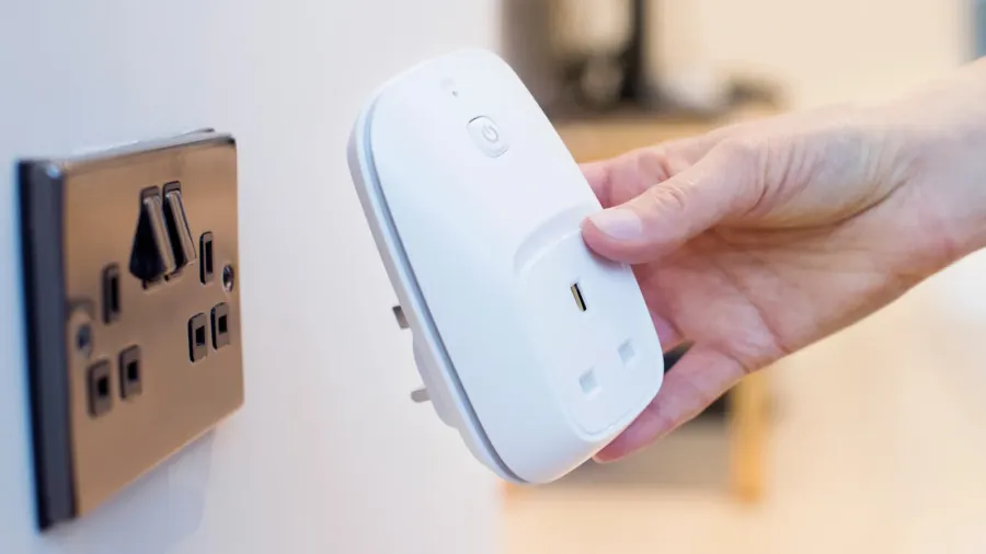 A woman plugging smart plug into a socket on the wall.