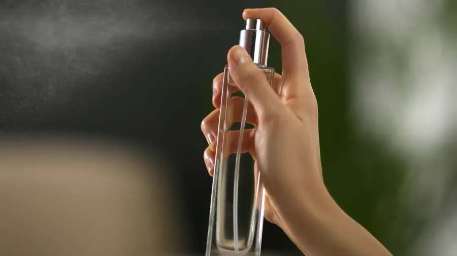 woman spraying air freshener at home closeup