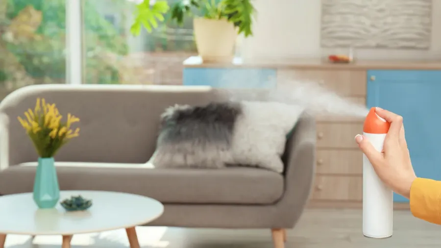 woman spraying air freshener at home