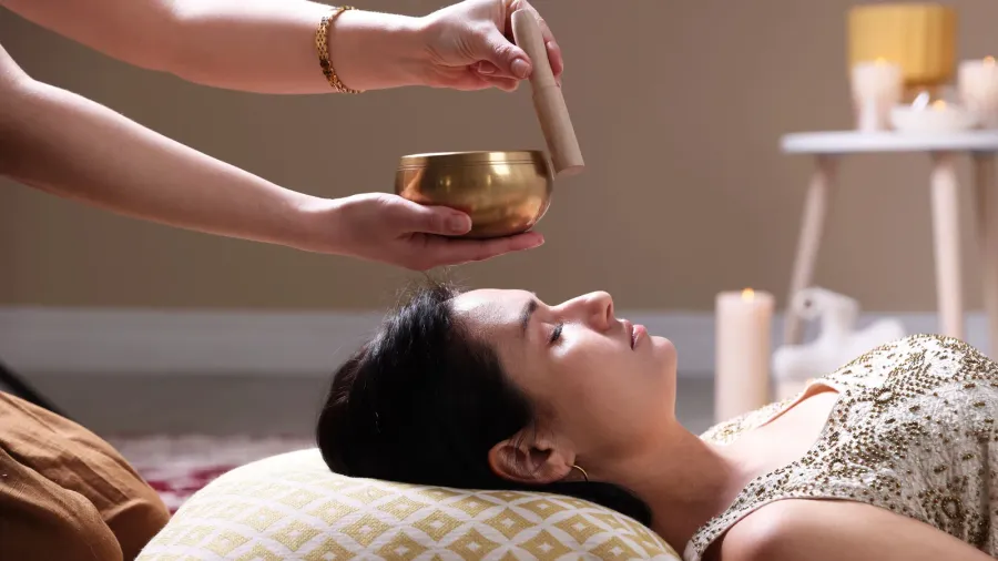 woman undergoing singing bowl therapy lying on floor indoors