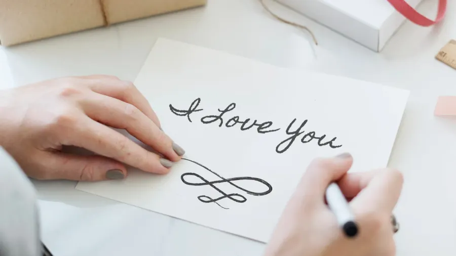 Handwriting a love note that says "Love You."