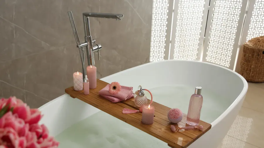 Bathtub with decorative candles, towels, and perfume bottles in a serene bathroom setting.