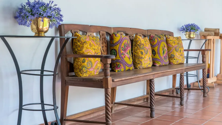 wooden bench with pillows and metal flowerpots with flowers near