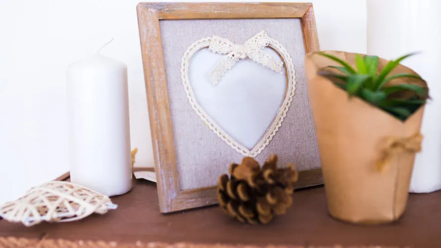 Decorative framed heart with lace ribbon and pine cone.