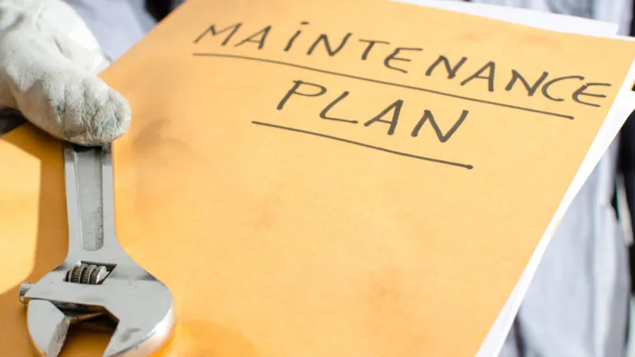 worker holding a folder of maintenance plan and monkey wrench