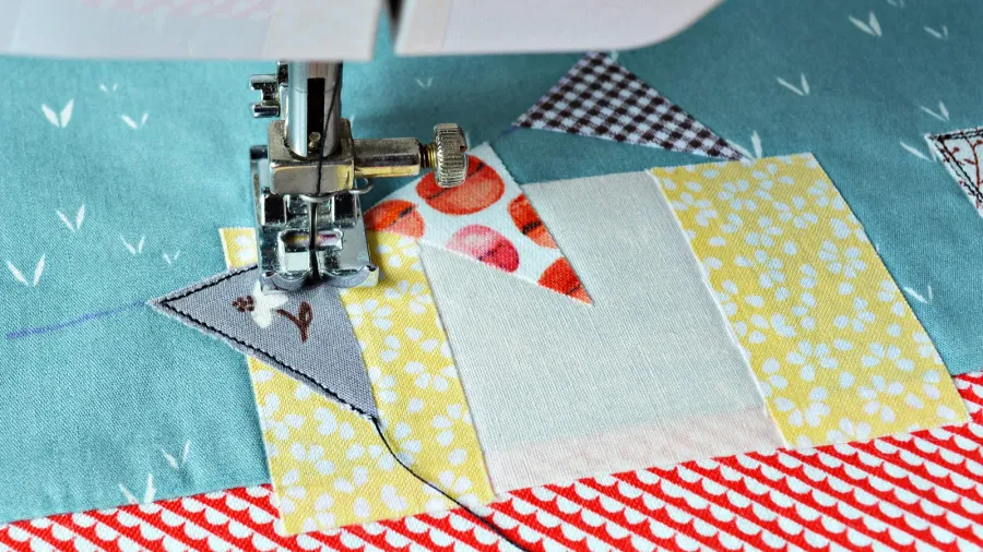 colorful and patterned fabric pieces being stitched together with a sewing machine.