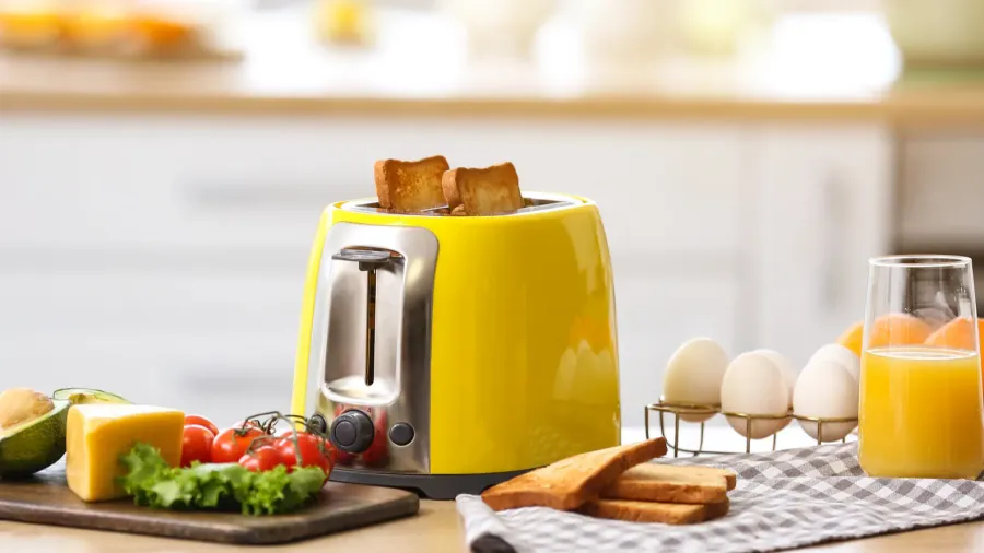 A bright yellow toaster with healthy food on table in a kitchen.