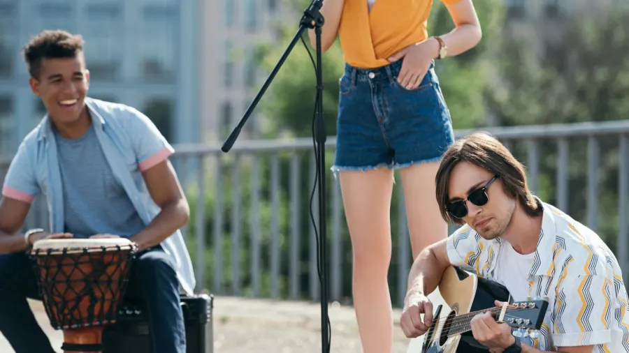 young and happy street musicians playing music and singingin city