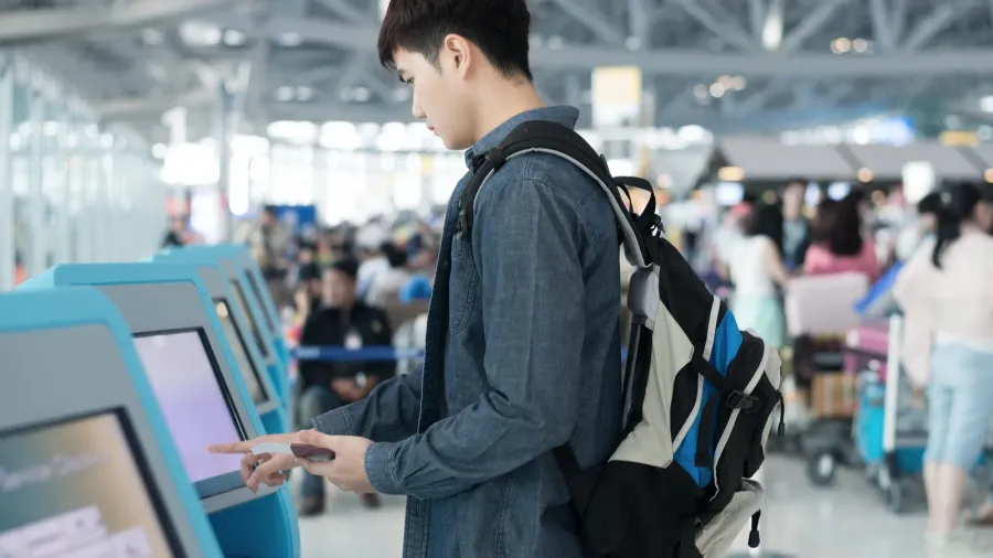 young asian man using self checkin kiosks in airport