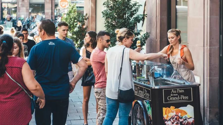 young blonde woman preparing icecream cone for client