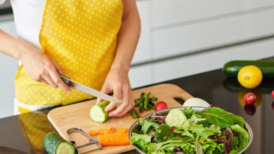 young caucasian woman with curly hair prepares a salad in