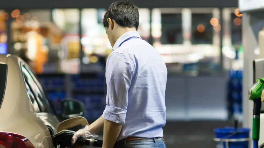 young man fueling his car at the gas station