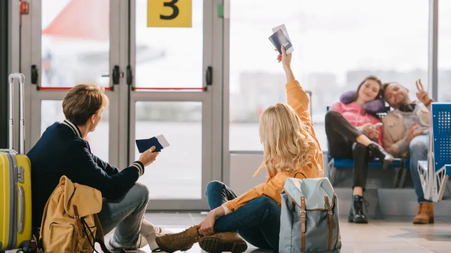 young travelers with passports and boarding passes greeting each other