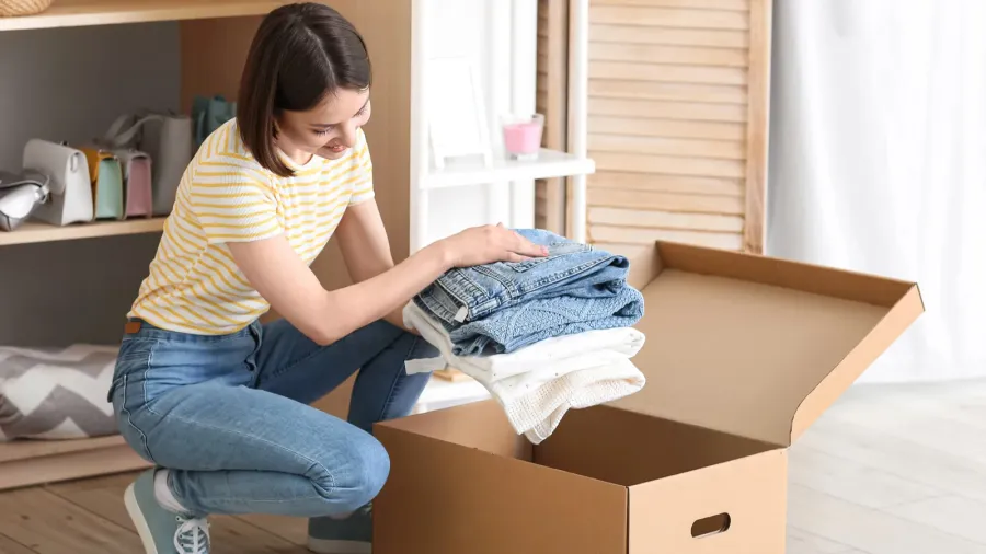 young woman arranging clothes at wardrobe