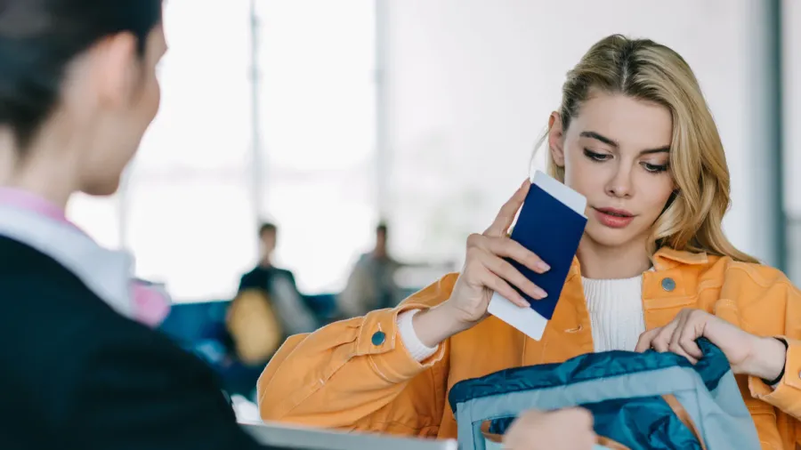 young woman putting passport with boarding pass into bag at