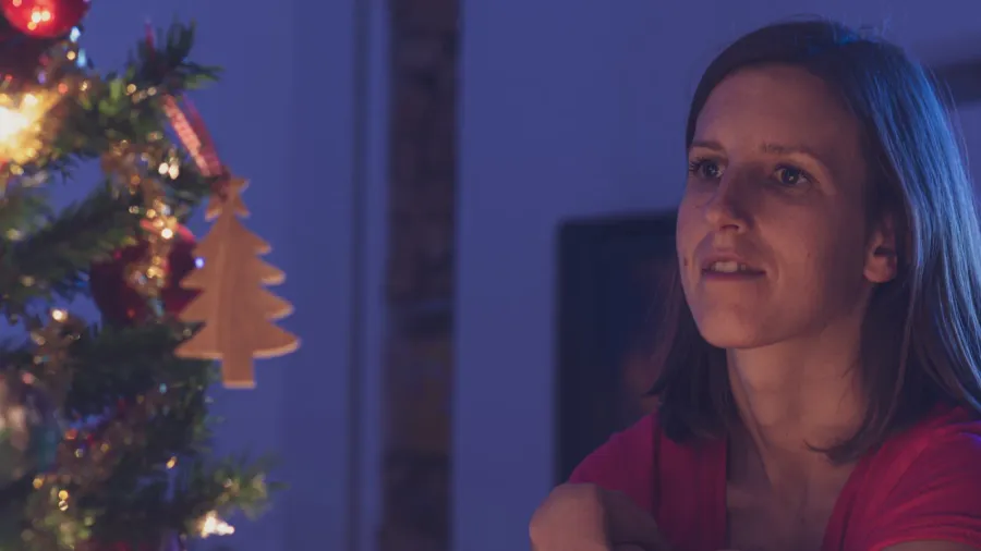 young woman sitting next to a christmas tree