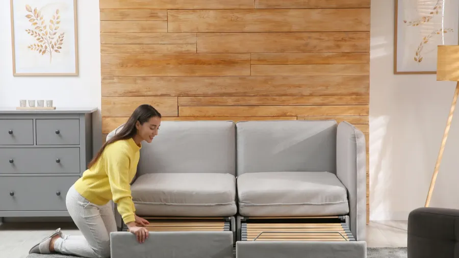 A young woman unfolding a modular sofa into a bed.