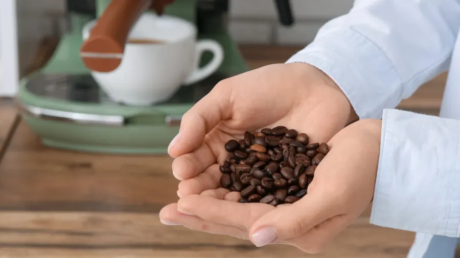 young woman with coffee beans in kitchen closeup