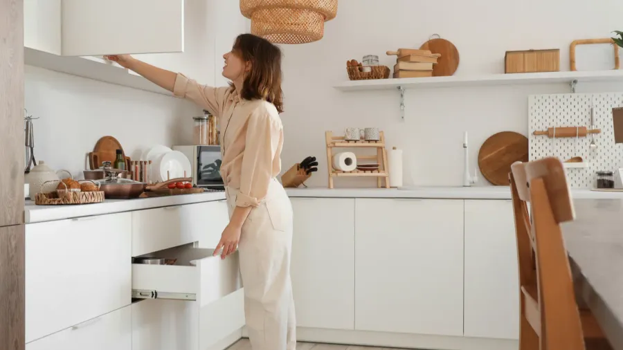 young woman with open drawer and cupboard in kitchen