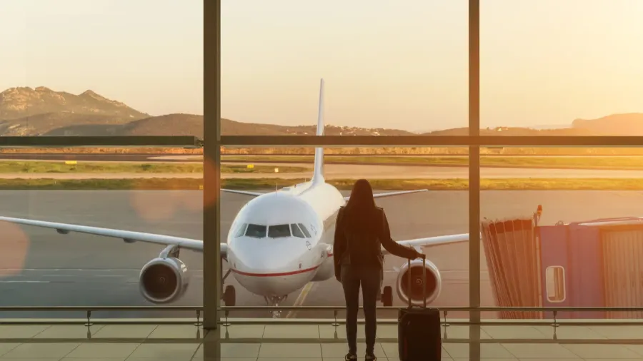 young woman with suitcase in the departure hall at airport